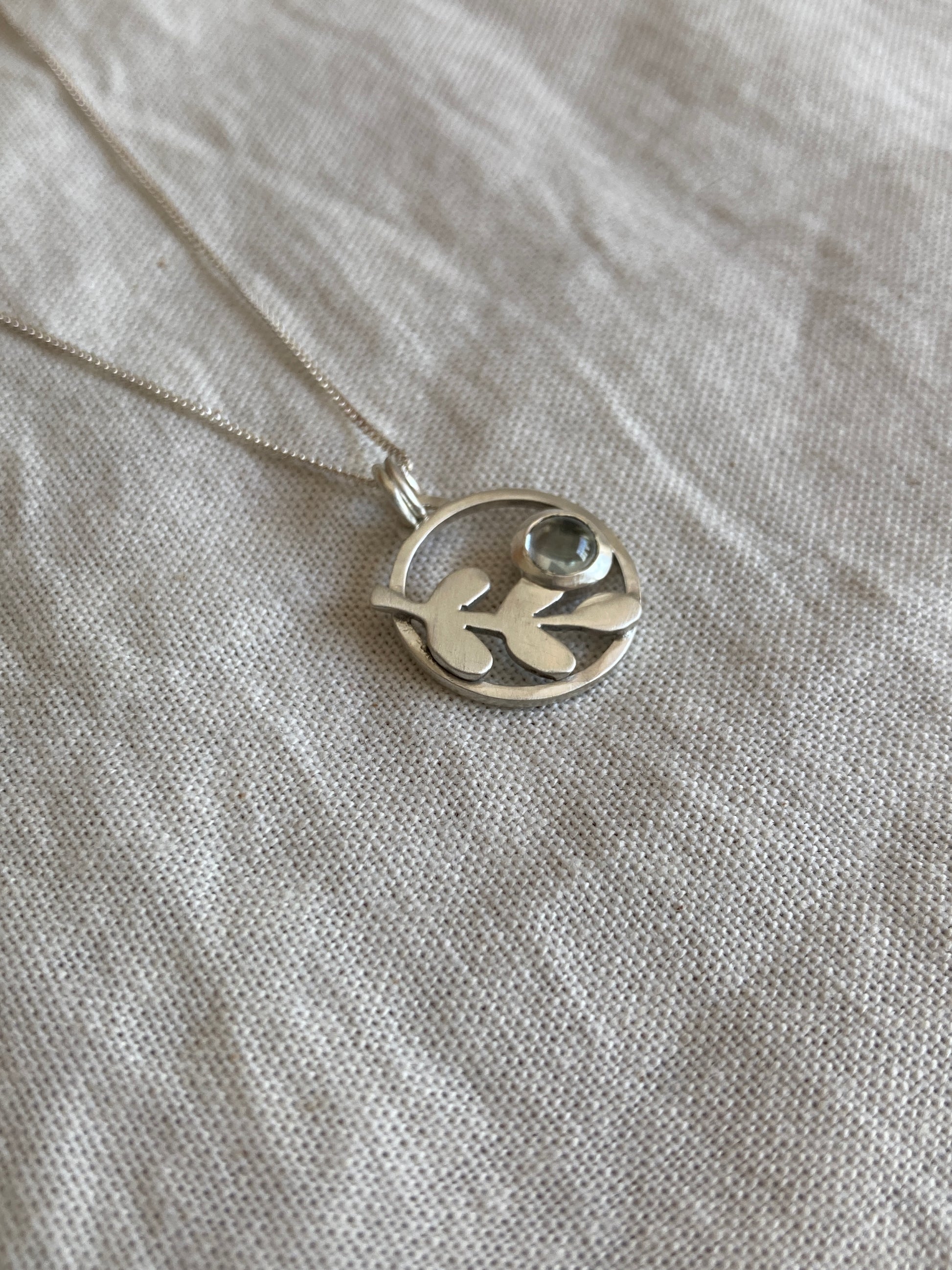 Sterling Silver Circle Pendant with Kiaat Leaves Detail and Set Blue Topaz Stone