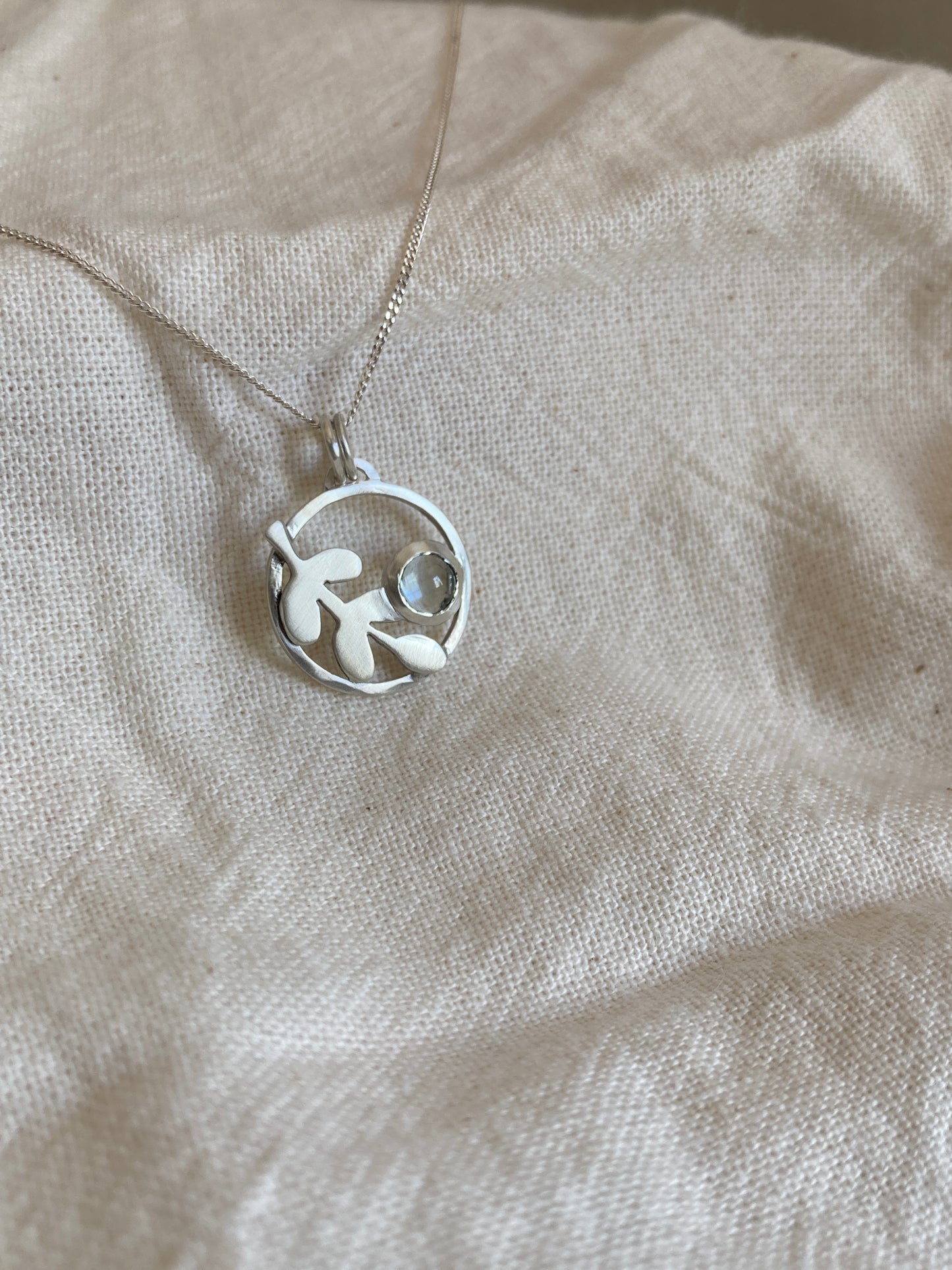 Sterling Silver Circle Pendant with Kiaat Leaves Detail and Set Blue Topaz Stone