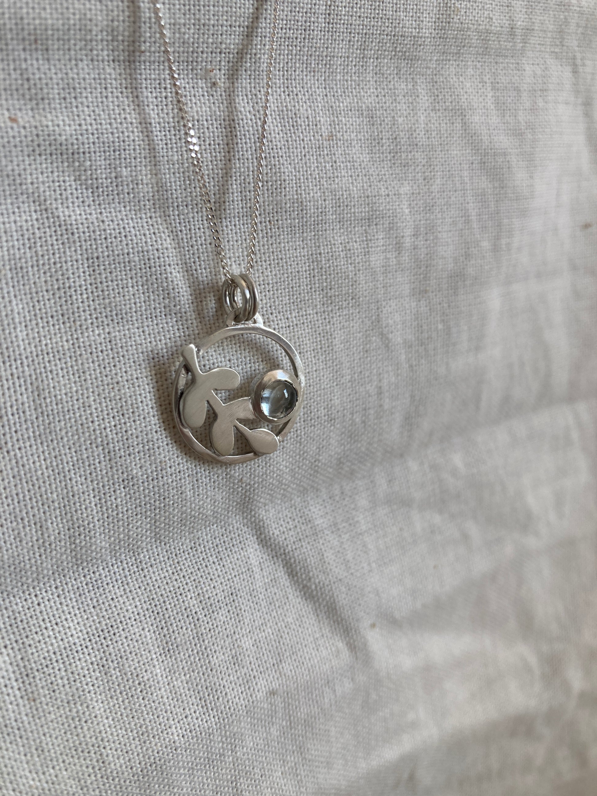 Sterling Silver Circle Pendant with Kiaat Leaves Detail and Set Blue Topaz Stone